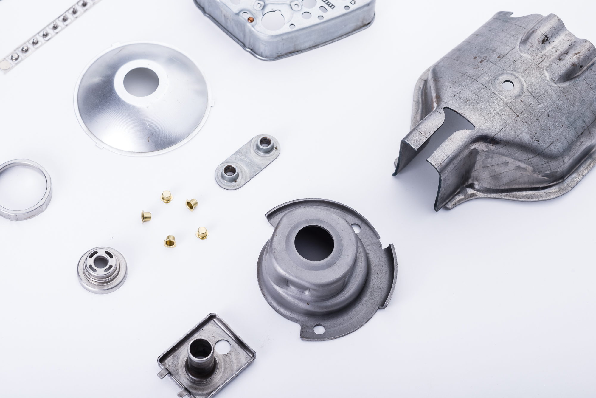 Tiefziehteile aus verschiedenen Werkstoffen vor weißem HIntergund